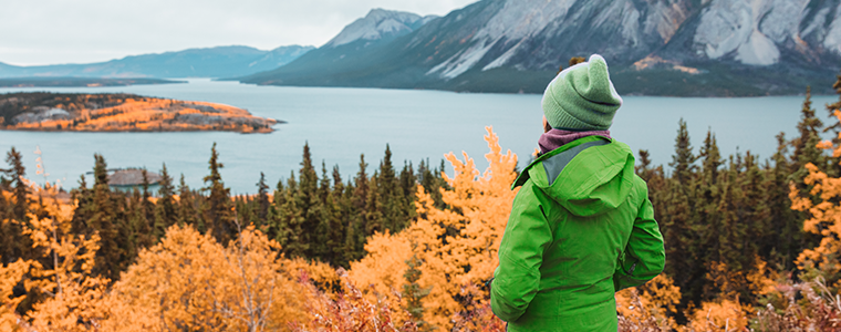 Hiker woman in green outerwaer at autumn fall mountains landscape.